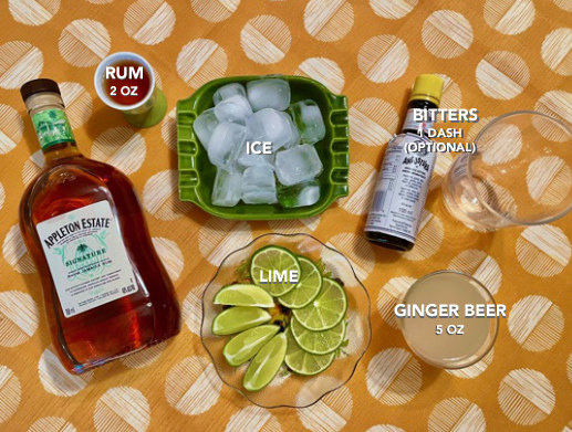 a bottle of appleton estate rum, a shot of rum, ice, lime, angostura bitters, ginger beer, rocks glass