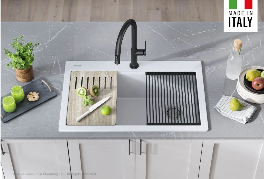 White drop-in kitchen sink with cutting board on left and black drying rack on right