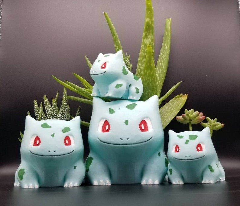 A family of Bulbasaurs in various sizes are displayed with small succulents in them