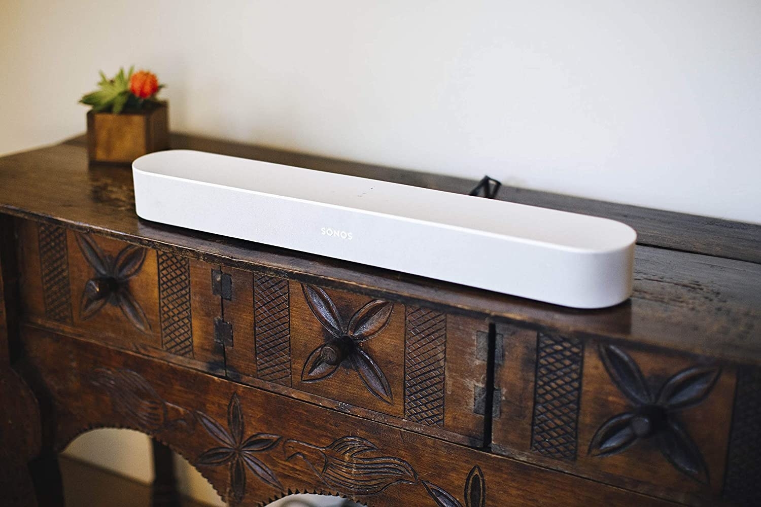 A long sound bar on a wooden TV stand