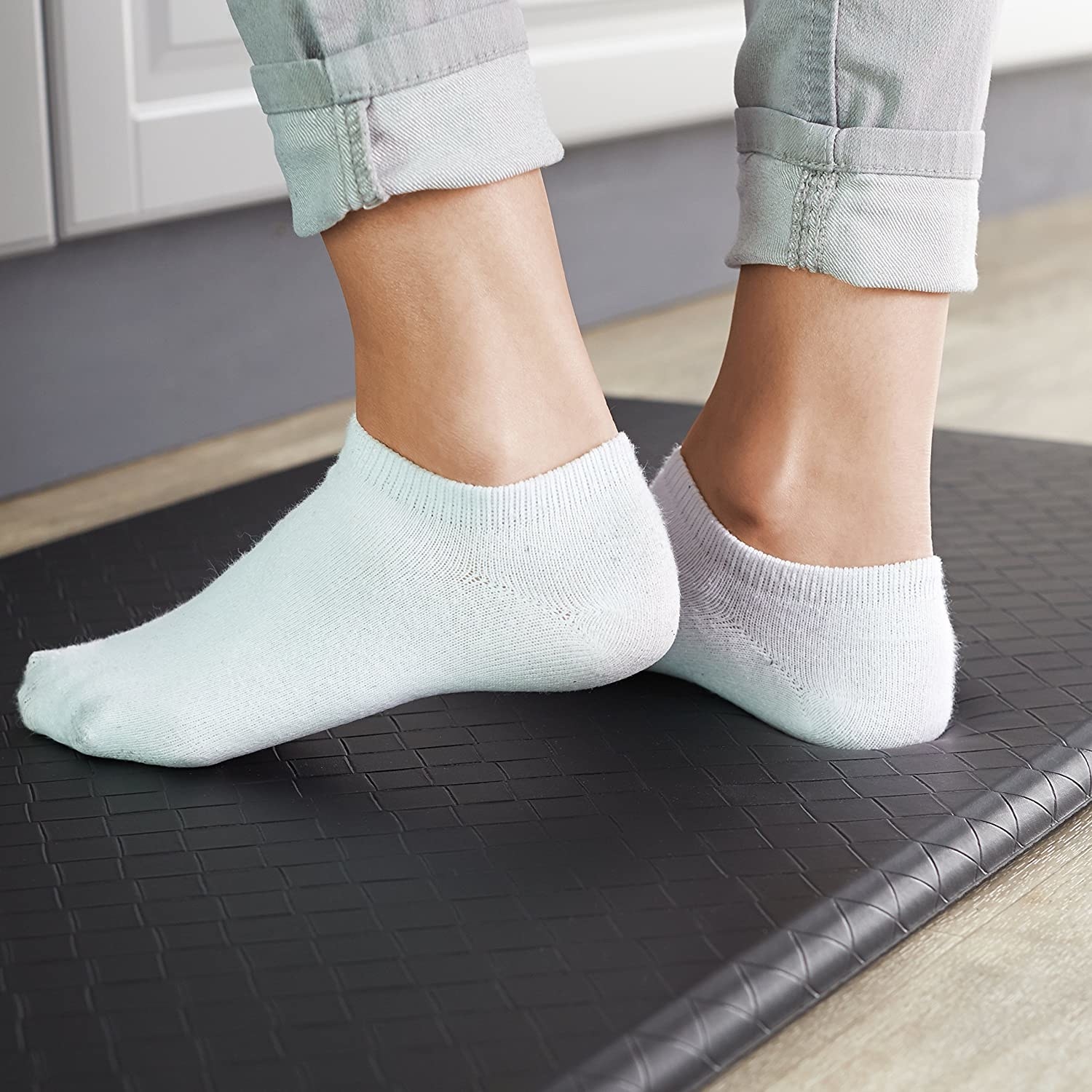 A person standing on a cushy mat in their kitchen