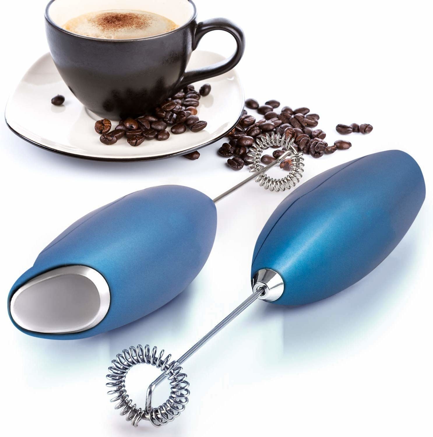 Two hand blenders lying next to a foamy cup of coffee and some coffee beans