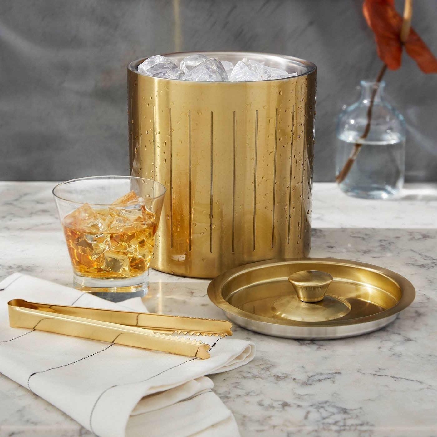 a gold ice bucket and matching tongs