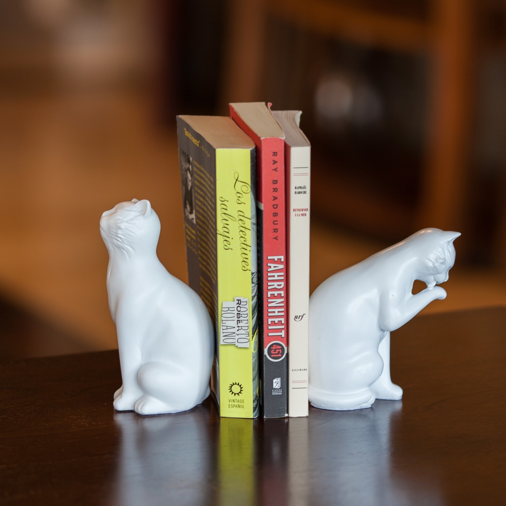 The white cat bookends on a bookshelf