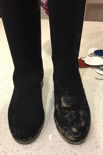 a reviewer's pair of black suede boots covered in dirt