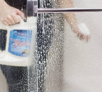 a model using the shower cleaner in a wet shower 