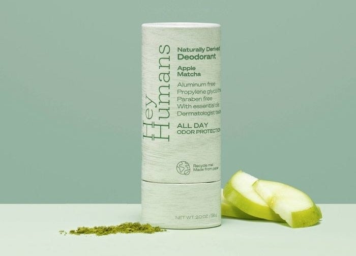 a paper tube of Hey Humans deodorant next to a pile of matcha and some apple slices
