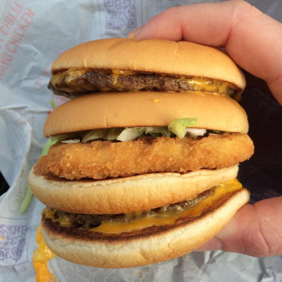 A McDonald&#x27;s burger with two beef patties and a breaded chicken patty.
