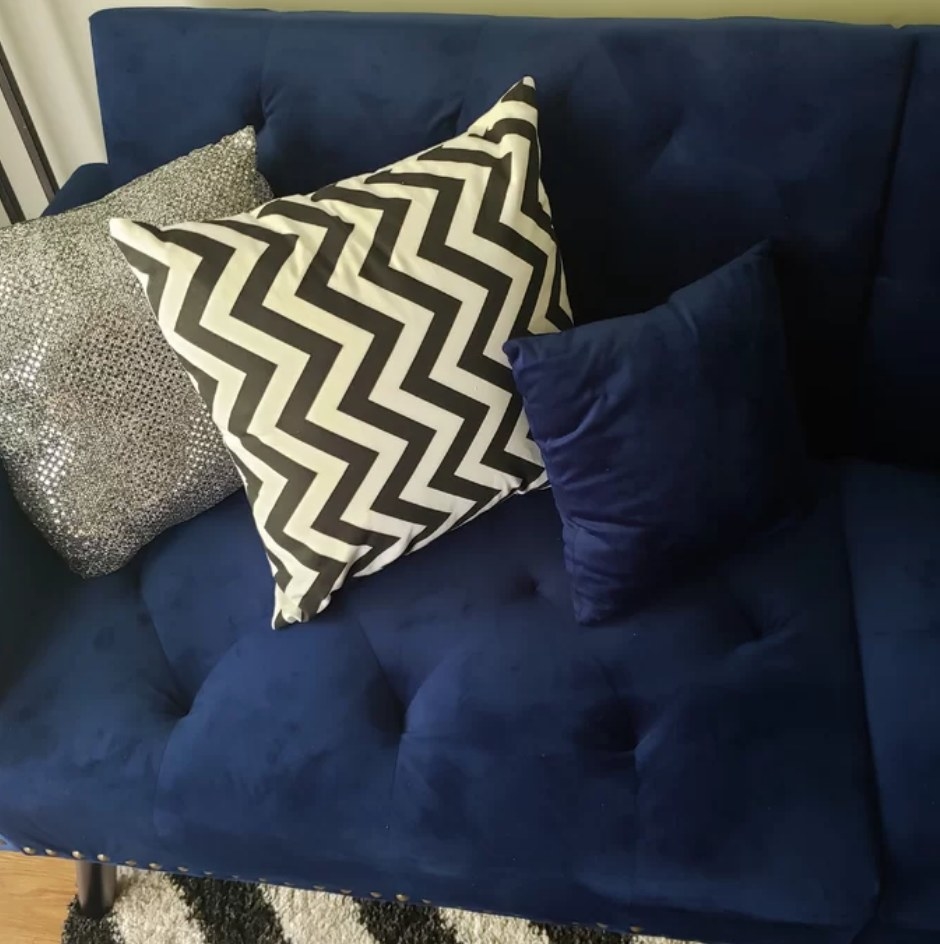 A reviewer&#x27;s black and white, chevron throw pillow atop a blue sofa