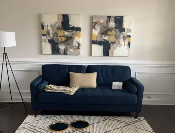 A reviewer&#x27;s navy blue, square arm, tufted sofa in a living room