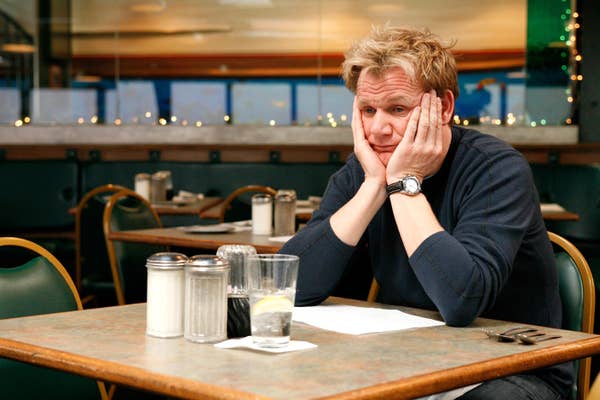 Gordon Ramsay looking sad at a table with his hands holding his face