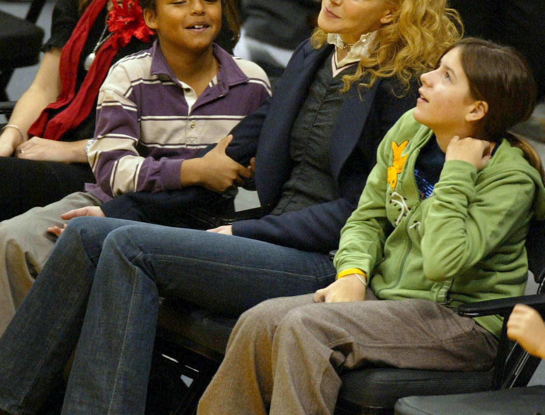 Bella sits next to Nicole and Connor court side at a basketball game