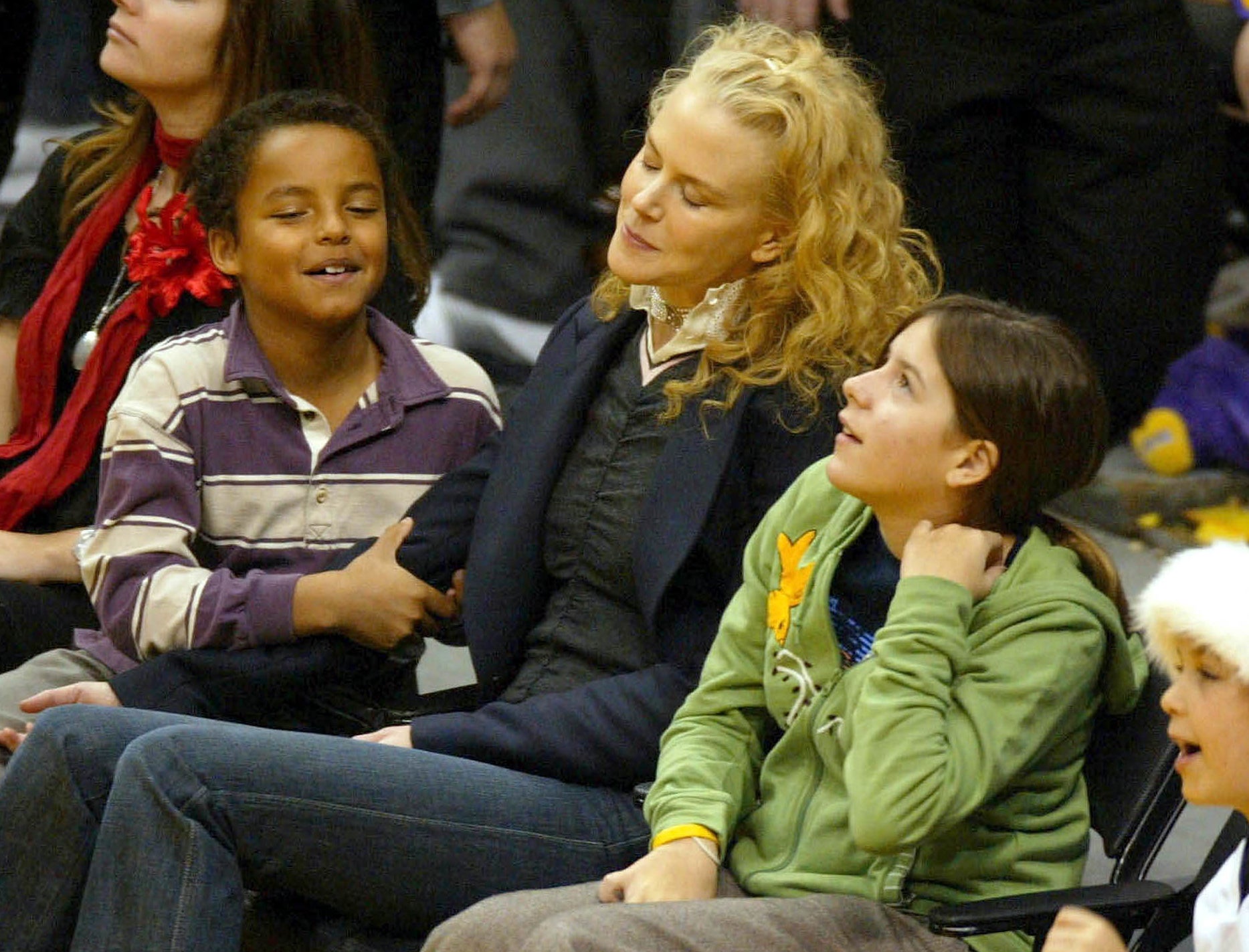 Bella sits next to Nicole and Connor court side at a basketball game