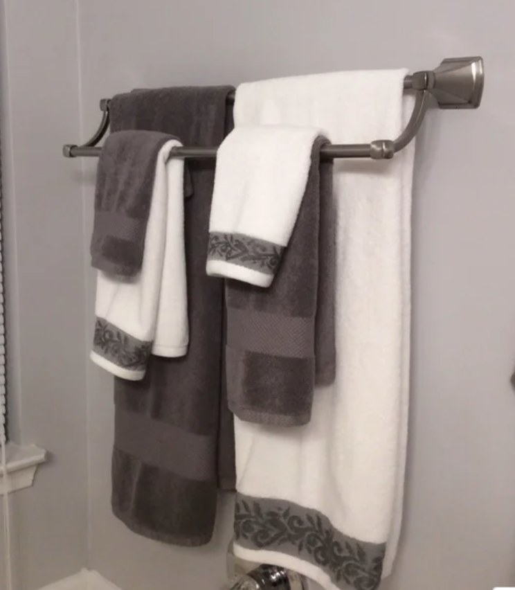 A reviewer&#x27;s 6-piece, 100% cotton towel set in white/charcoal hanging from a rod in a bathroom