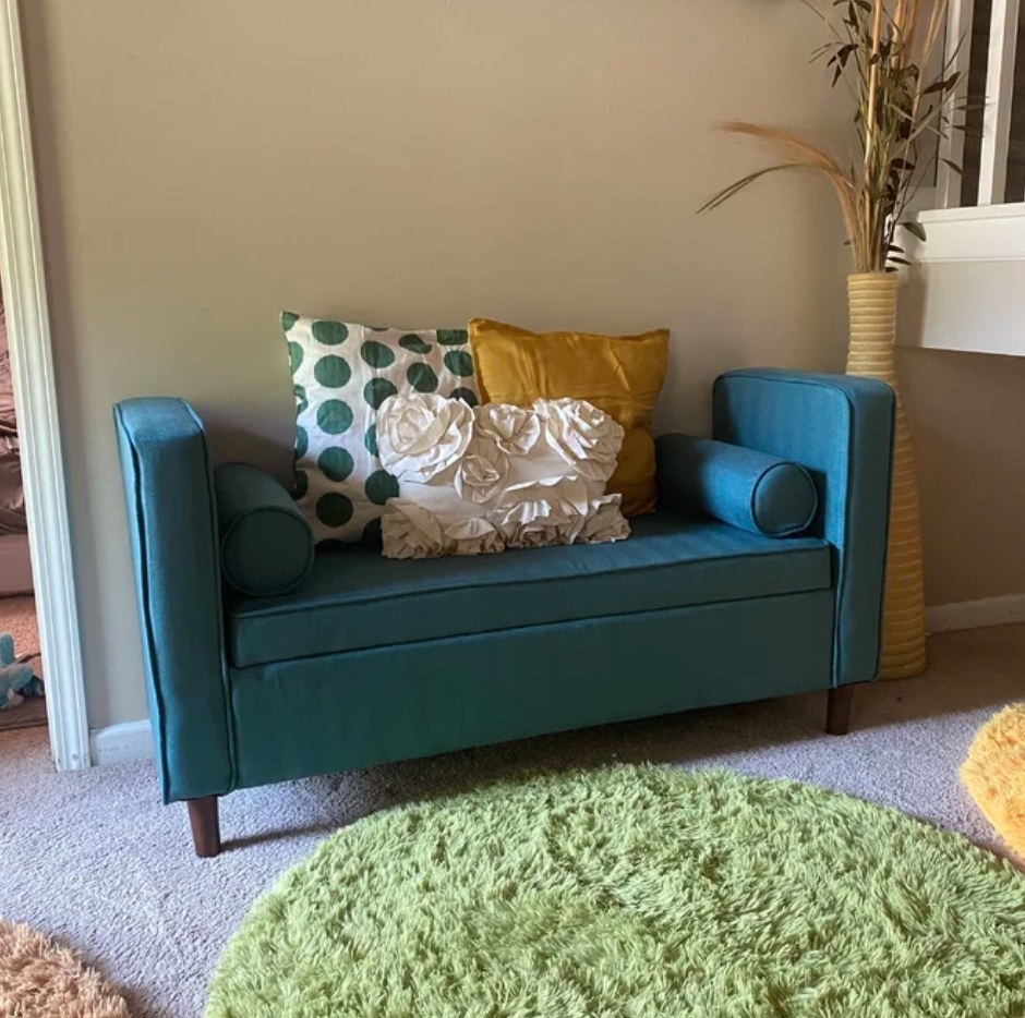 A reviewer&#x27;s teal, flip top storage bench with two matching pillows