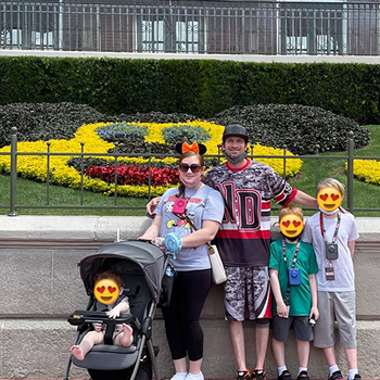 Reviewer with their family at Disney using the blue fan which is attached to the stroller