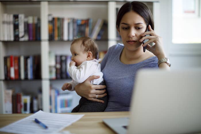 Woman trying to work from home while holding a baby