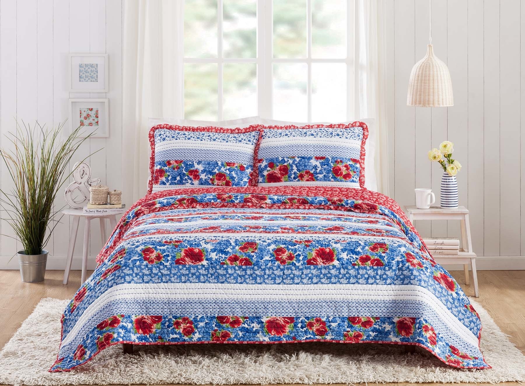 The set on a bed, looking great. It has bands of fabric in shades of blue with red accents. Some of the patterns are floral, and some are geometric.