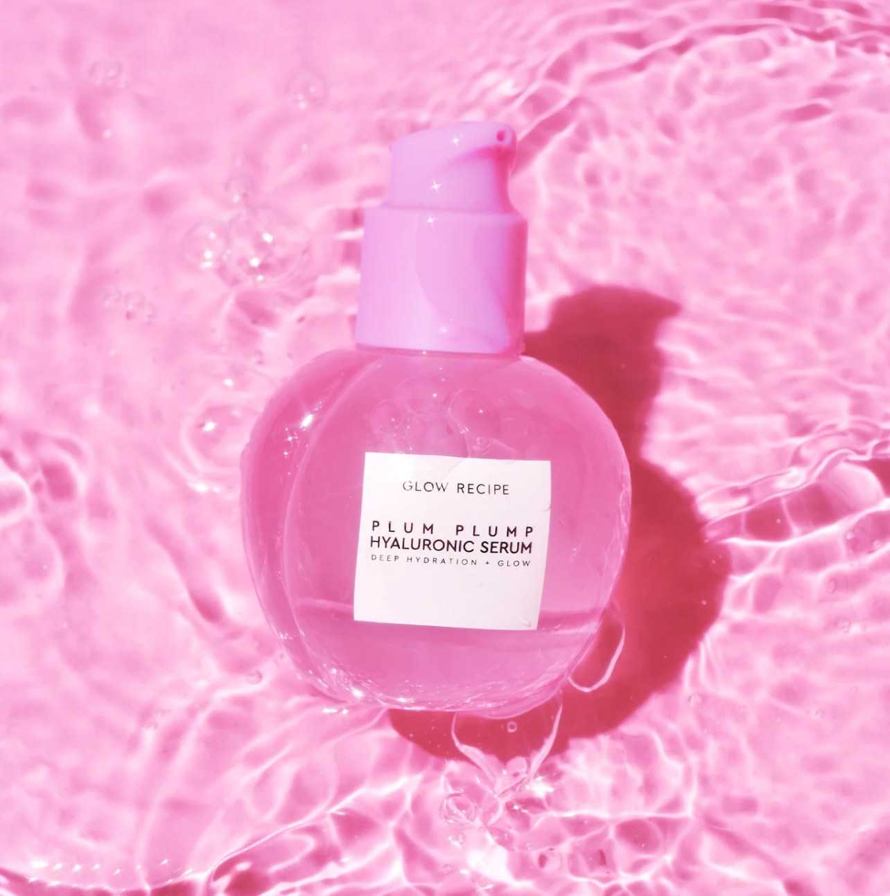 Bottle of glow recipe plum plump against pink water background