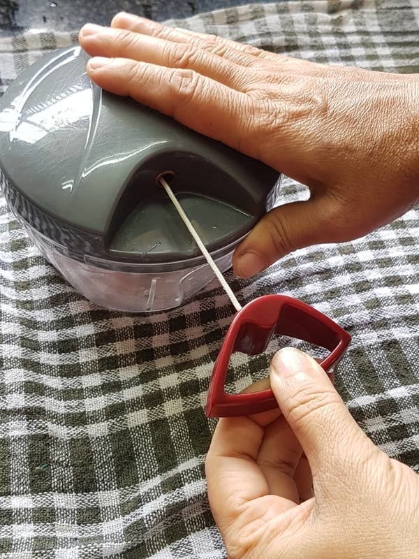 A person&#x27;s hand pulling the vegetable chopper