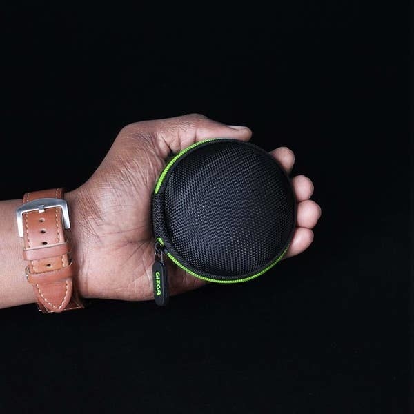 A hand holding a green and black earphone case