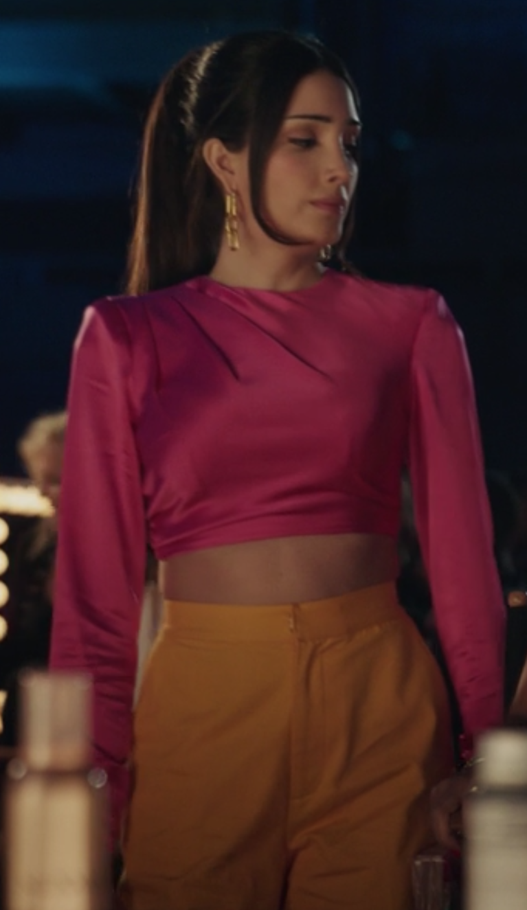 Luna wears a cropped long sleeve pink shirt and high waisted orange pants.