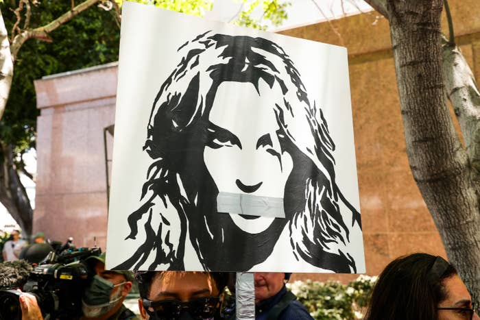 A protester holding up a sign with an image of Britney with tape over her mouth