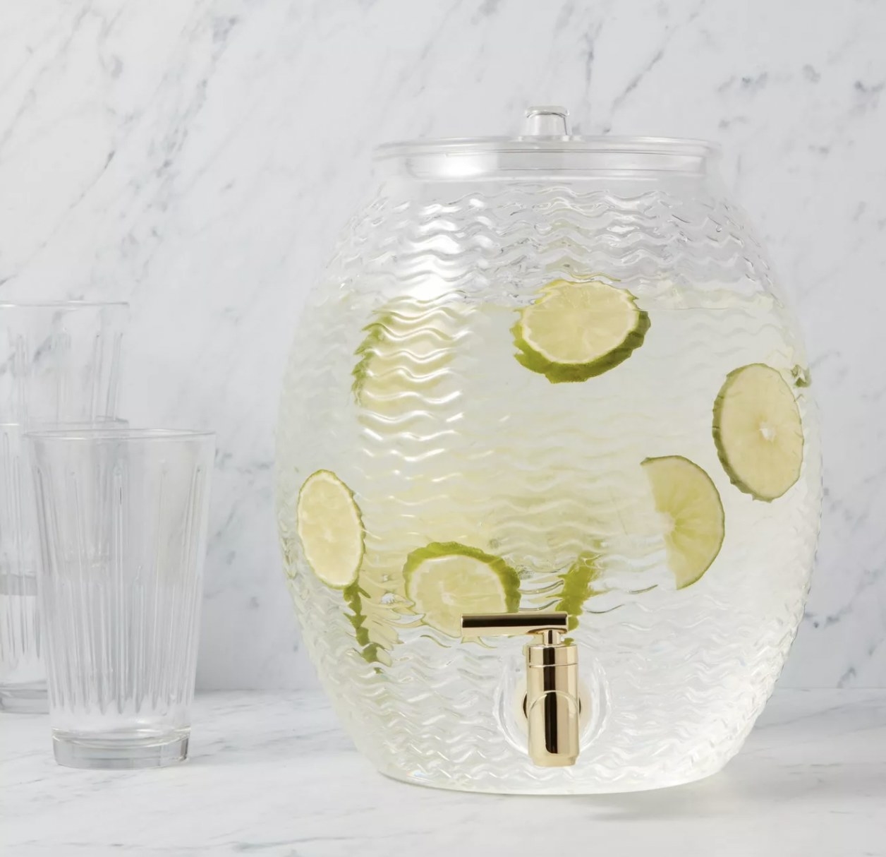 a clear beverage dispenser with a gold nozzle