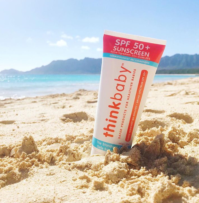 SPF 50+ bottle of sunscreen in the sand