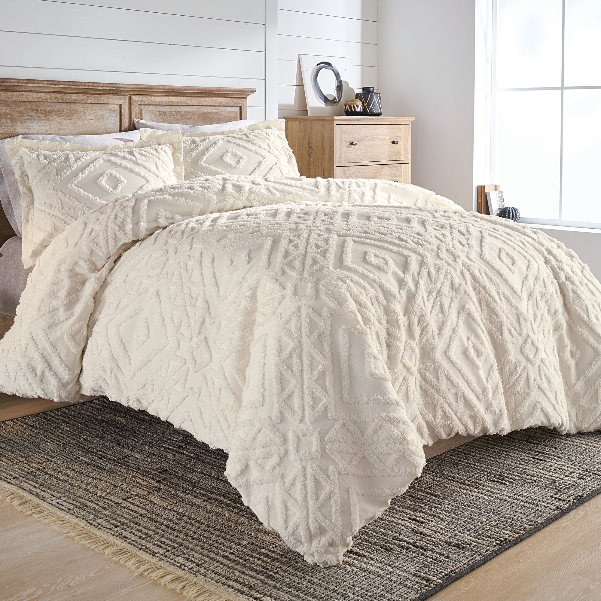 The white patterned duvet cover and shams on a bed