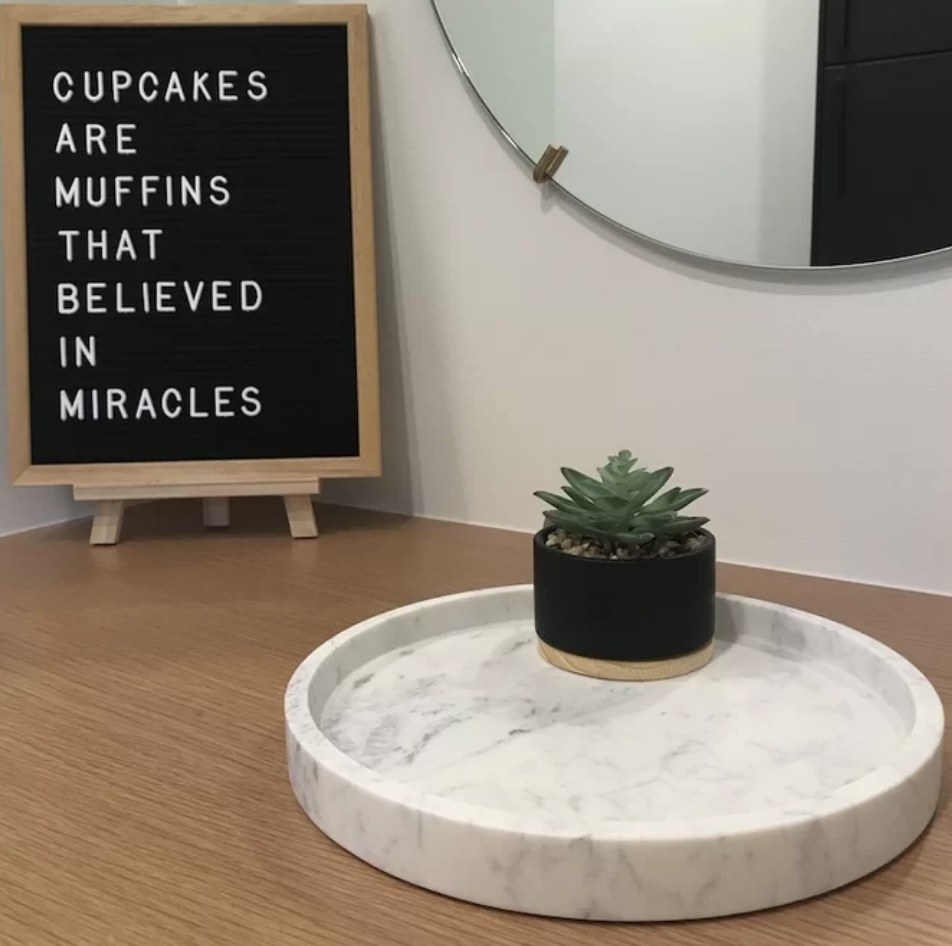 A reviewer&#x27;s round, marble coffee table tray with a succulent atop