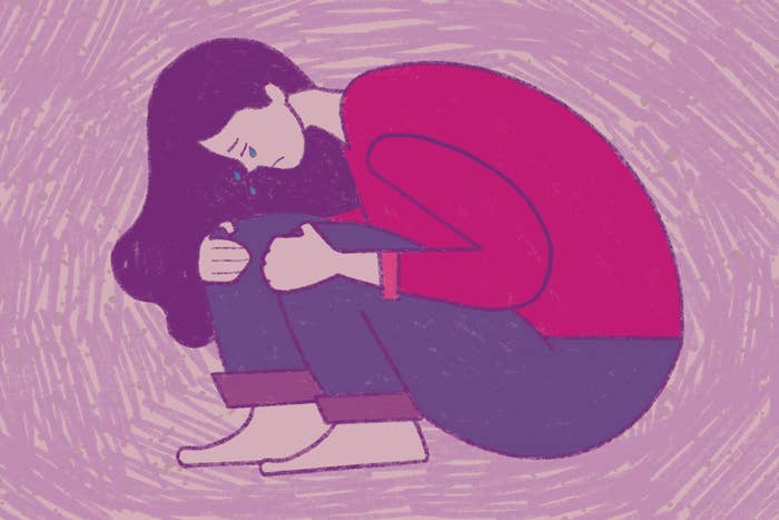 An illustrated image of a crying woman hugging her knees to her chest