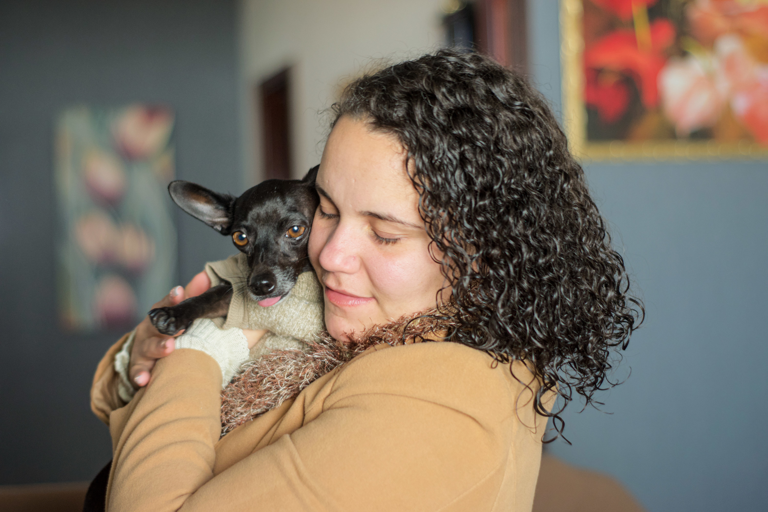A young woman cuddles with her miniature pinscher dog