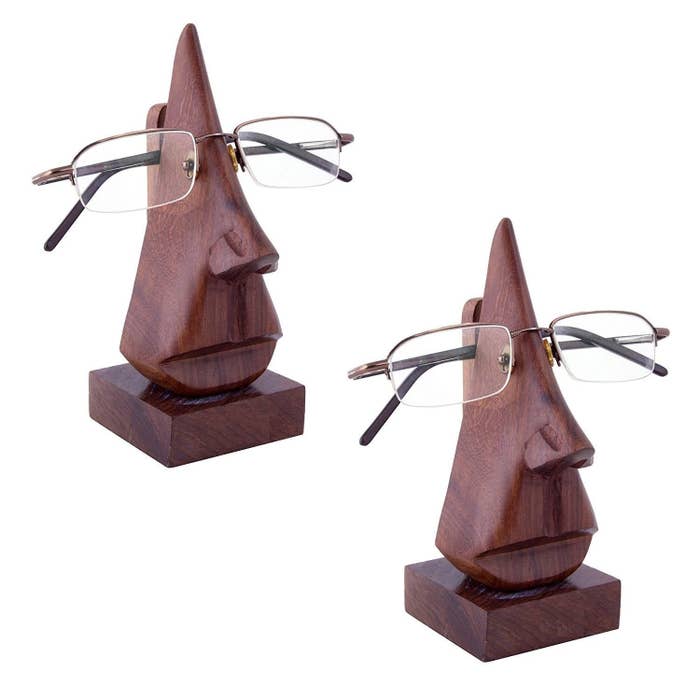 Two wooden spectacle holders shaped like heads, with two specs resting on their noses
