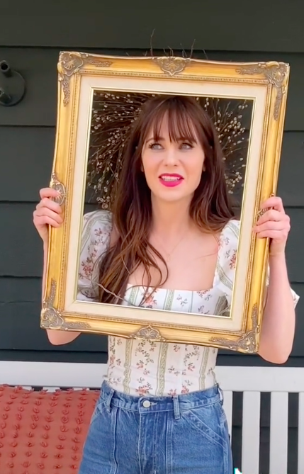 Zooey looking through a picture frame held up to her face