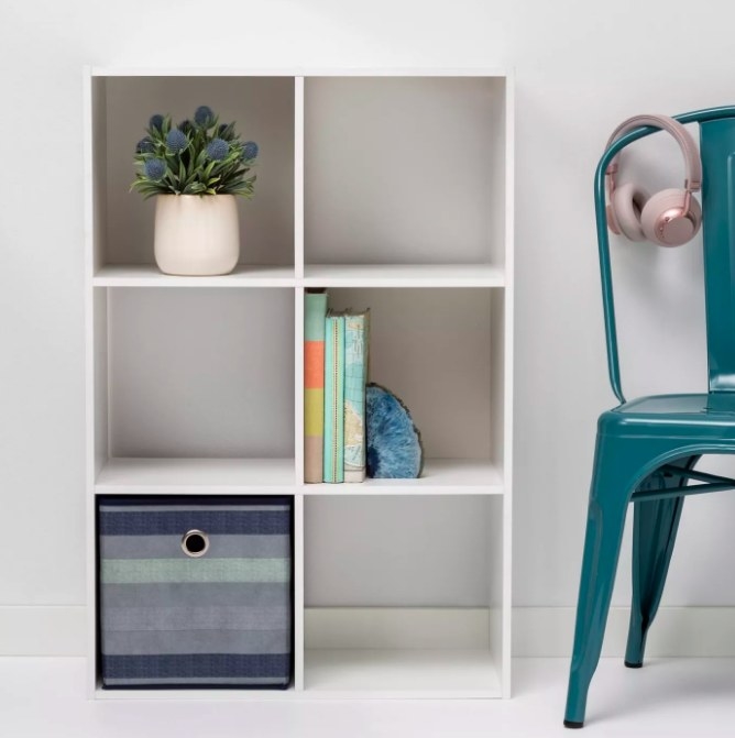 The white organizer storing a plant, books, and bin