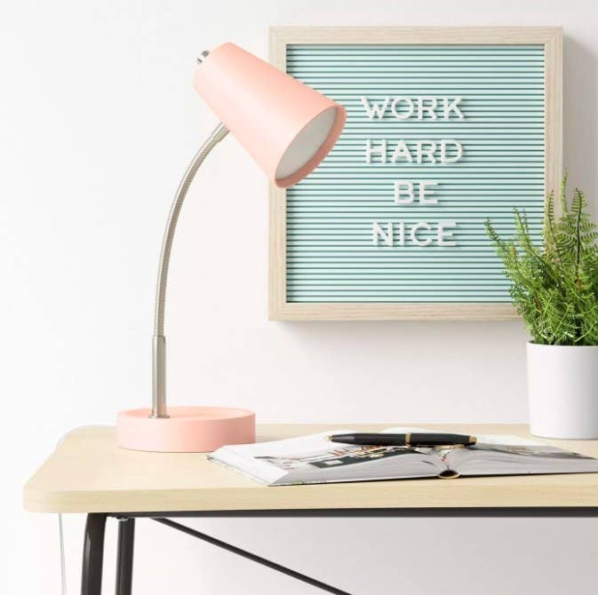 The blue letterboard on the wall behind the desk with the message &quot;work hard be nice&quot;