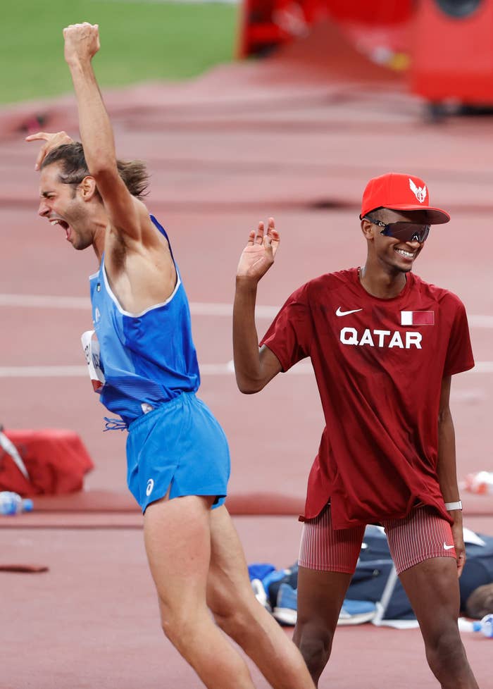 Tamberi raises his hands as Barshim smiles