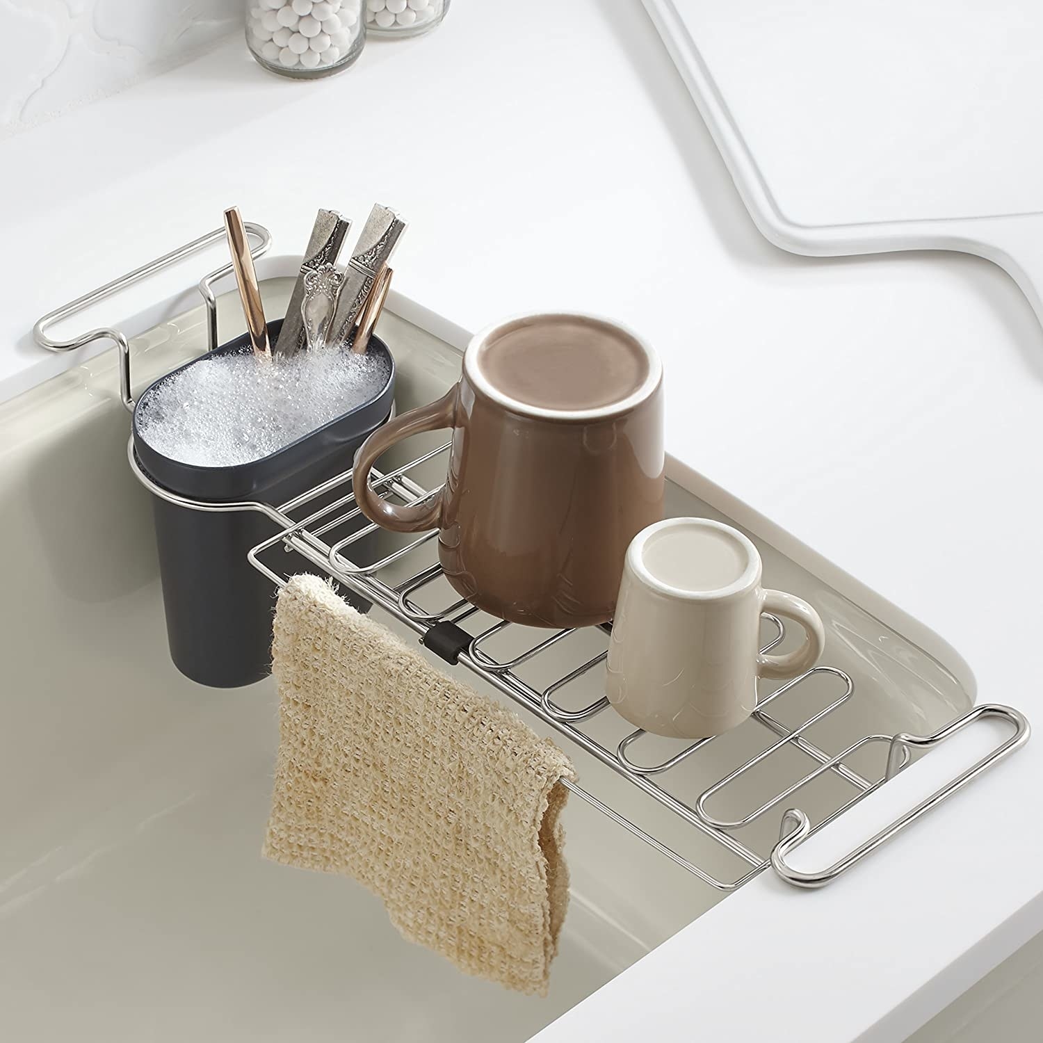 The rack with mugs on it and utensils soaking in the cup