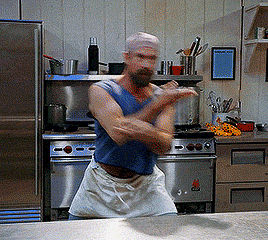 Meloni as Chef Gene in Wet Hot American Summer dancing behind an industrial table in the camp kitchen