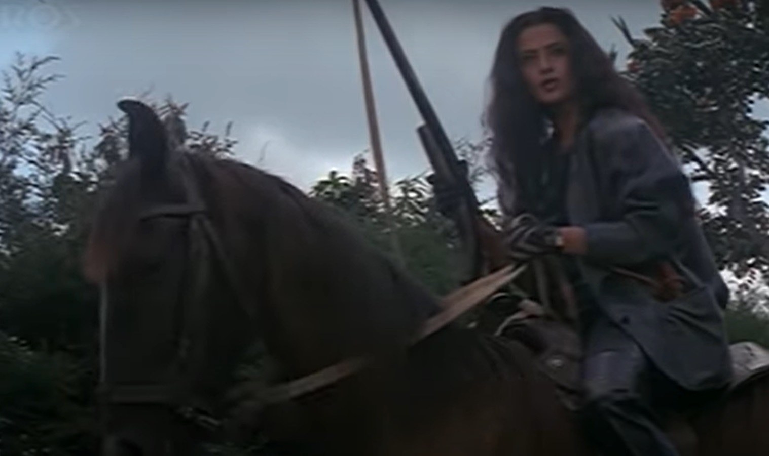 Nandini sits atop a horse and brandishes a rifle