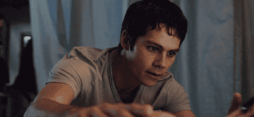 dylan o&#x27;brien in maze runner, wears a t-shirt, is concerned and strokes the face of a woman