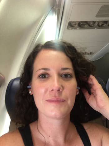 reviewer on an airplane with the earplugs in
