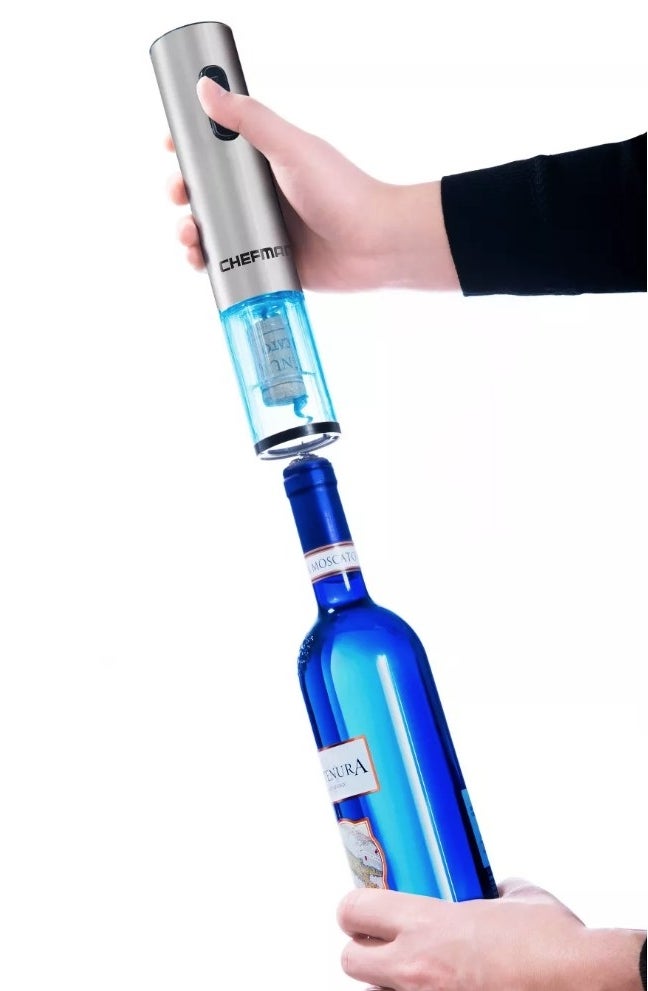 A model using a stainless steel, electric bottle opener on a wine bottle