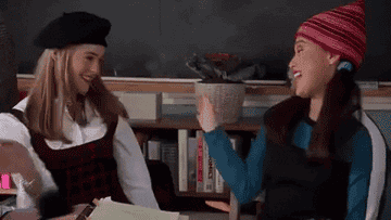 Cher and Dionne from a scene in Clueless high-fiving in class