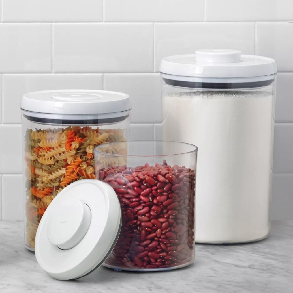 Three clear airtight canisters filled with food on a counter
