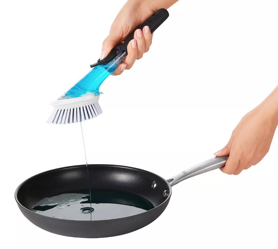 A model using the soap-dispensing dish brush on a pot