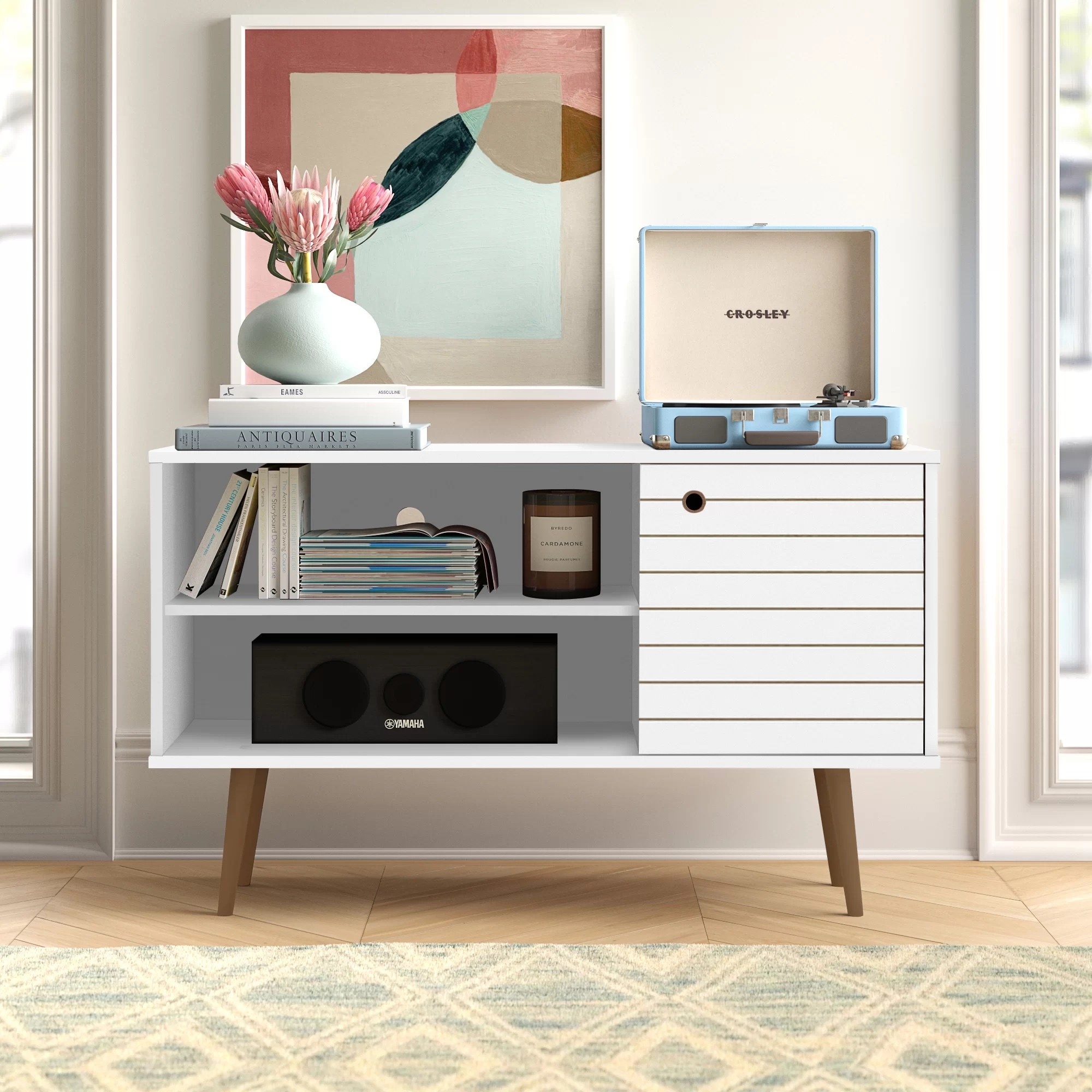 A tv stand holding a stereo, vinyl record player, books, and a vase