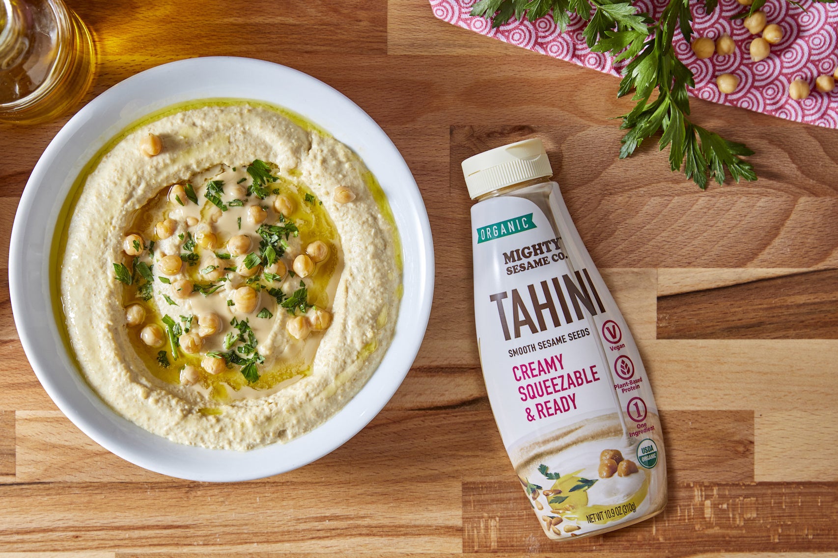 A table with hummus, chickpeas, and a bottle of tahini on it