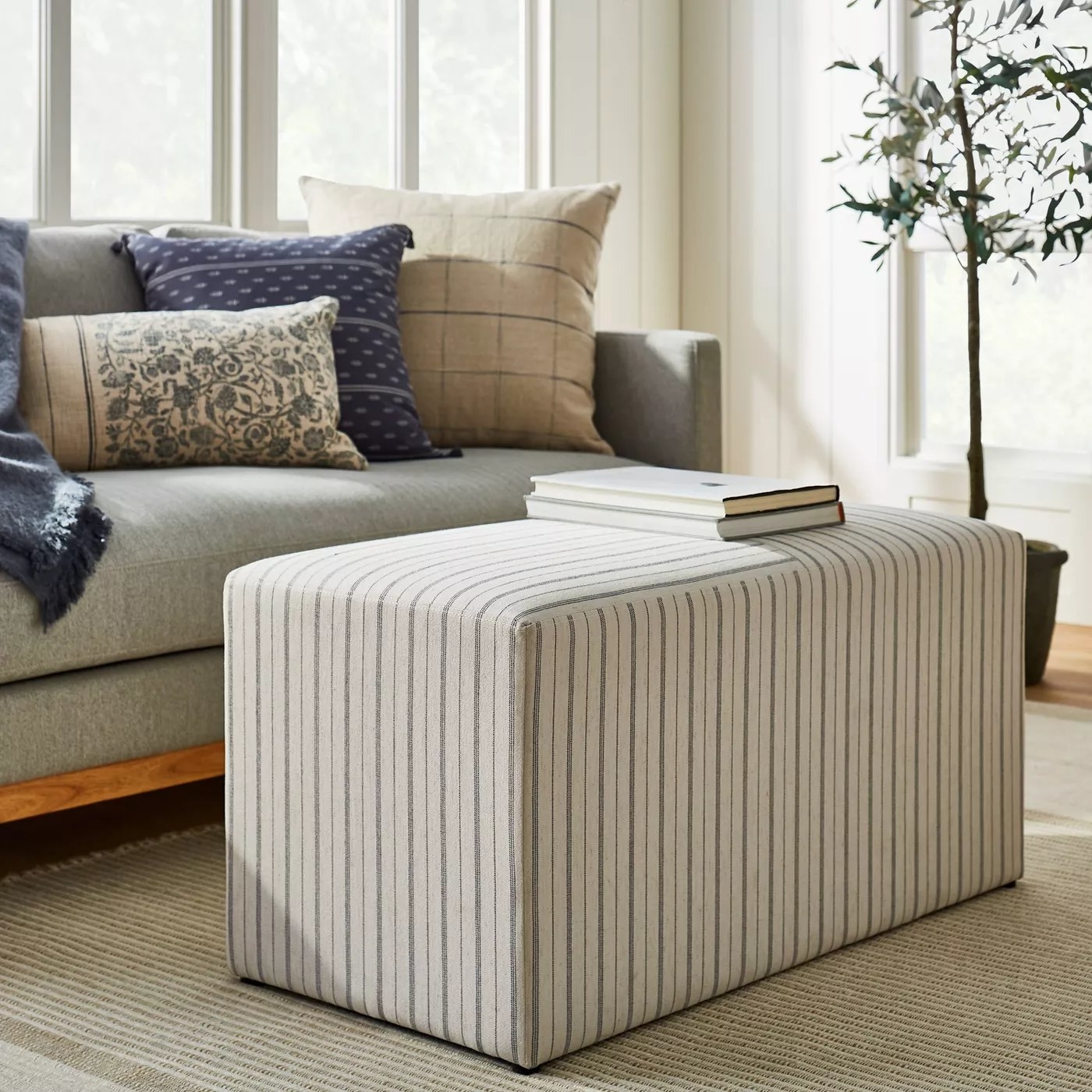 The upholstered cube being used as a coffee table in a living room